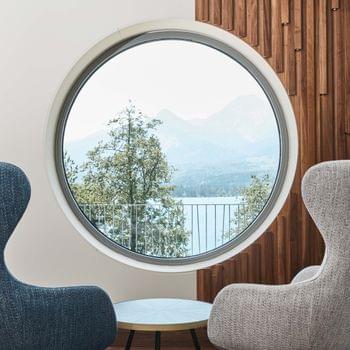 Wellnessansatz Moderne Loungesessel vor rundem Fenster mit Blick auf See und Berge